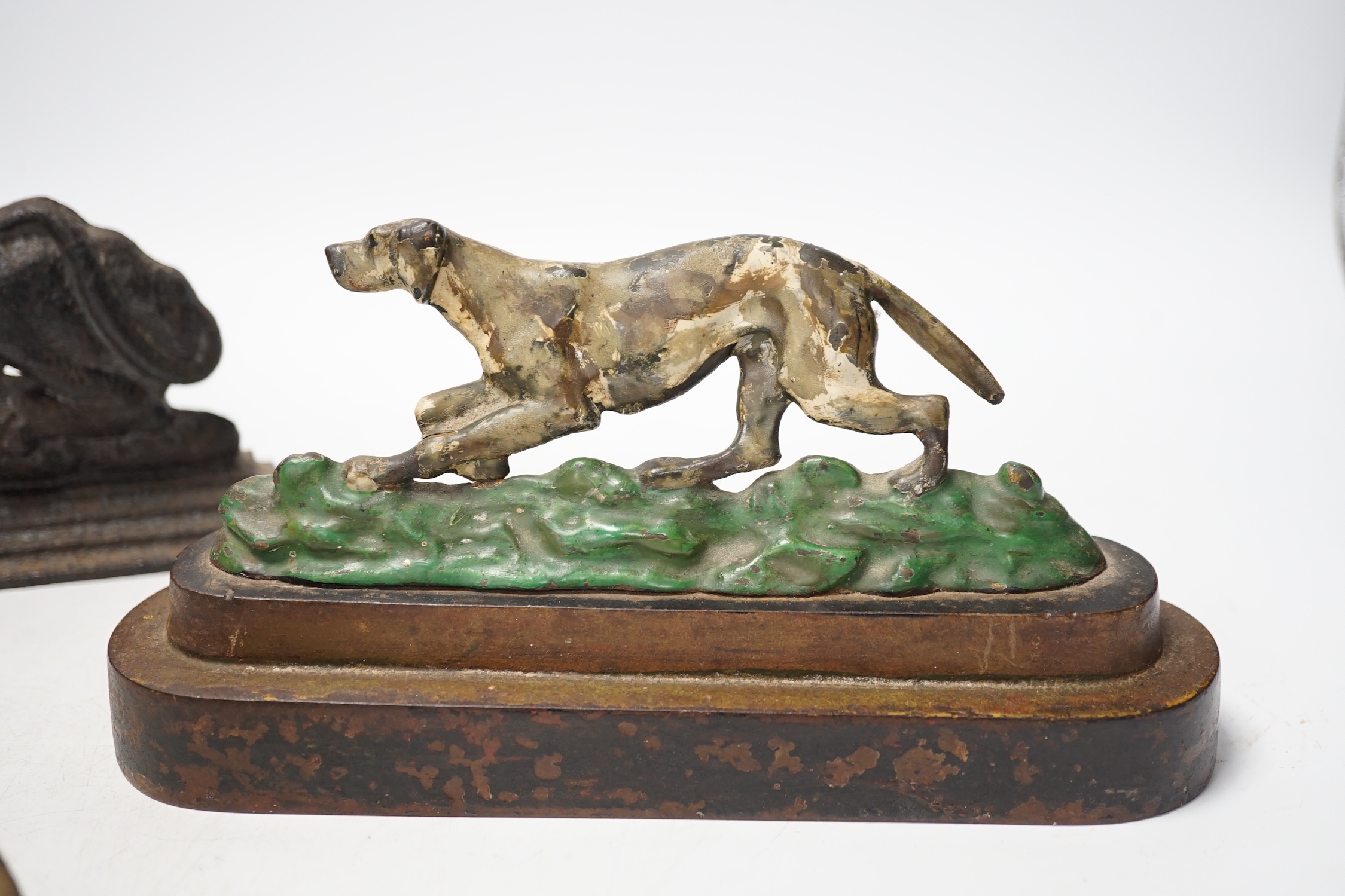 Two cast iron lion door stops and a painted dog door stop, 21cm wide